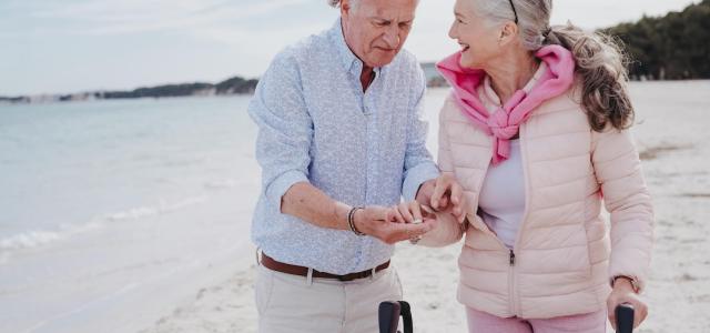 older man and woman with walker laughing alongside the beach 