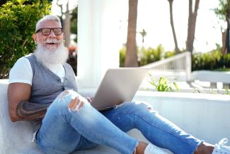 LGBTQ+ muscle senior with glasses working on the computer