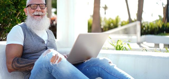 LGBTQ+ muscle senior with glasses working on the computer